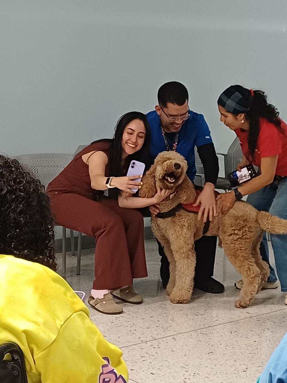 Funcionarios de salud tomando selfie con perro terapeuta golden